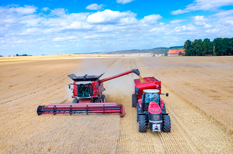 Traktor og tresker driver innhøsting på et jorde